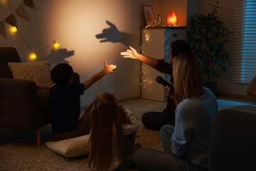 Shadow play. Father and his son making hand gestures like dogs on wall at home