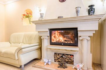 Cozy interior with a burning fireplace, decorated mantlepiece with ornaments, and comfortable...