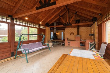 Cozy outdoor covered patio with a brick grill, wooden table and chairs, and a comfortable swing.