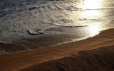 Ocean shore close-up. Wet sand. Sea foam. Waves. Color image. Poster. Wallpaper. Background. Postcard.