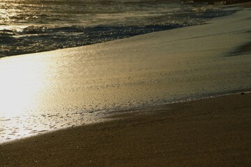 Ocean shore close-up. Wet sand. Sea foam. Waves. Color image. Poster. Wallpaper. Background. Postcard.