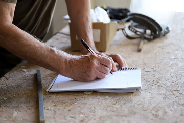 
Detail of an elderly man's hands taking notes in a workshop