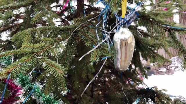 Christmas tree with a small object hanging from it. The object is a small, round, yellow object with a blue and yellow string