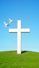 White cross on green hill with flying doves against blue sky