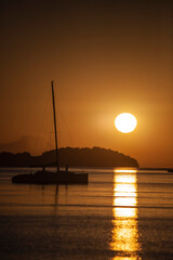 Silhouette of a sailboat with sunrise in the background off the coast of Brazil