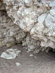 Rugged rock formation surrounding a sandy area with natural textures. Holiday vibes, serenity and exploration in a coastal environment