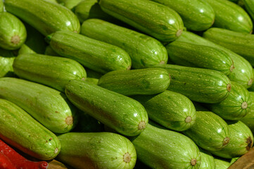 Freshly harvested green zucchinis stacked together at a vibrant local market in mid-summer sunshine