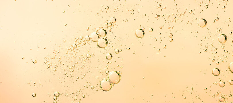 Macro of yellow golden liquid with many bubbles. Bubbles of different sizes and shapes, creating a textural effect on a light background.