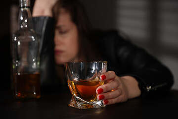 Alcohol addiction. Woman with glass of whiskey at table, selective focus