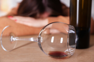 Alcohol addiction. Miserable woman with wine at table indoors, selective focus