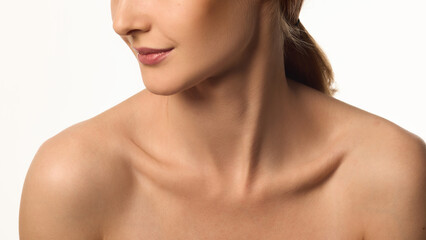 Cropped image of female face, neck and bare shoulders, young woman with glowing skin, emphasizing neck and jawline beauty. Concept of natural beauty, skin care, cosmetics, wellness, and healthy glow.
