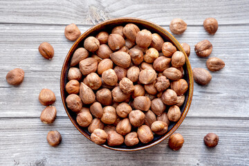 Photograph of dried hazelnuts without shell in a bowl on wooden background. Top view.  Healthy eating and snack, whole foods. Source of natural fats, minerals and vitamins. 