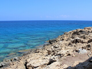 Beautiful seascape with a rocky beach and clear blue calm sea water. Northern Cyprus nature background. Karpas peninsula. 