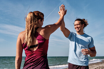 Personal trainers giving high five after successful workout on beach
