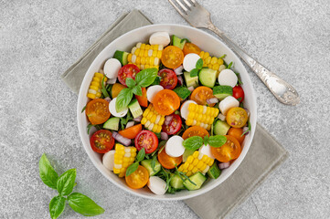 Sweet corn salad with arugula, tomatoes, cucumber, red onion and mozzarella. Healthy food. Top view.