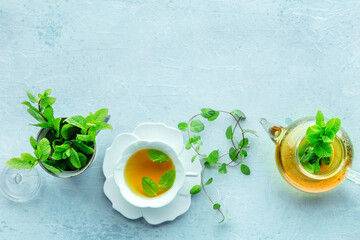 Mint tea. A cup of peppermint tea with fresh mint leaves and a tea pot, overhead flat lay shot on a...