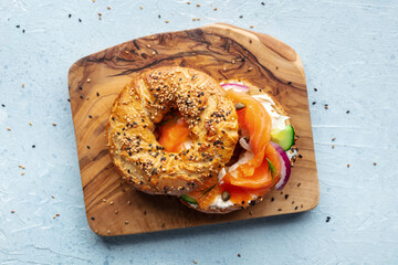 Lox bagel. A sandwich with smoked salmon and fresh vegetables on a wooden board, overhead flat lay shot