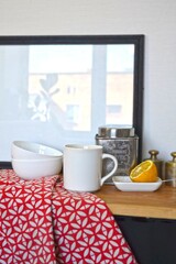 Kitchen still life with a white mug, bowls, tea caddy and a lemon