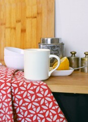 Close-up of a white mug with lemon and weights on a kitchen counter
