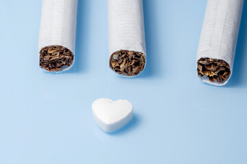 The medical concept of diseases of the human cardiovascular system. Cigarettes and a pill in the shape of a heart. Selective focus