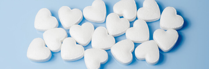The medical concept of diseases of the human cardiovascular system. A heart-shaped tablet on a blue background. Selective focus. Panoramic photo.