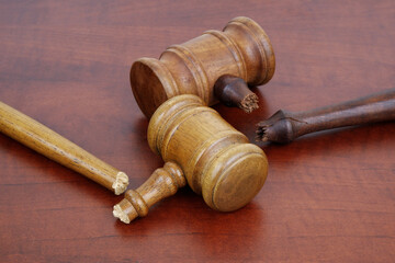 Two broken wooden judge gavels on table. Concept of iniquity, injustice and not working laws.