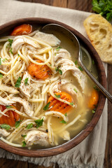 Bowl of chicken noodle soup with carrots on a napkin