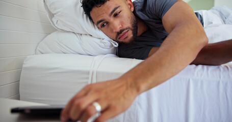 Obraz premium Man, bed and wake up with phone alarm for morning routine, start day and sound alert in home. Sleepy, person and mobile notification in bedroom to get up, lazy weekend and awake with smartphone app