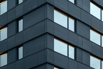 Obraz premium Corner view of dark modern building with reflective windows, minimal geometric architecture and clean design lines