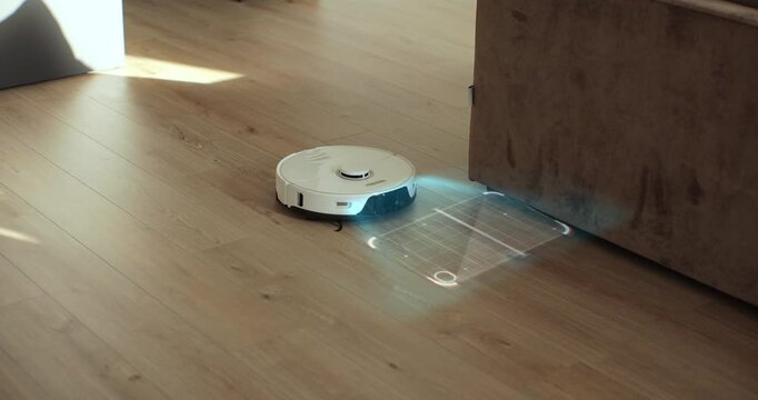 White robot vacuum cleaner scan laminate wood floor. Detectors help to recognize walls and objects and optimize cleaning. Smart futuristic cleaning device. Creates cleaning map. Technology concept