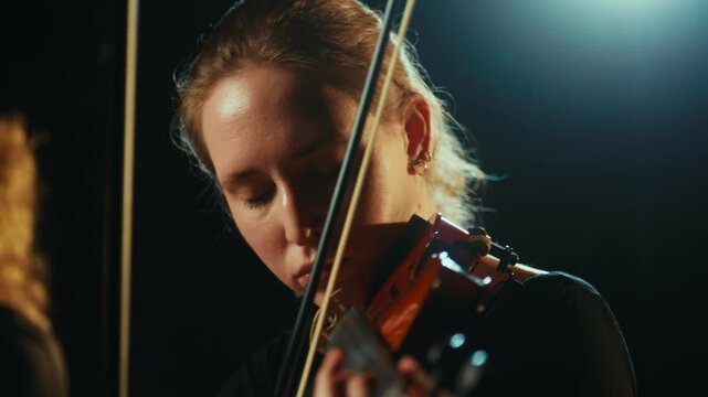 Play violin and enjoy music, young woman expressing emotions by art, portrait. Beautiful female musician performing contemporary classical music on stage, reflection in mirror and rain in background