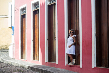 Beautiful woman wearing sunglasses next to an old door posing for photo. Happy smiling person.