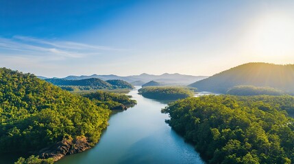 Aerial view of a wide river flanked by mangrove forests, with low flat mountains, green vegetation, rocks, clear sky and water reflecting in a charming, tranquil natural landscape.