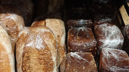 Regular yeast-free bread loafs in bakery or grocery store. Freshly baked in shopping display, close-up. White and brown loaves of bread.