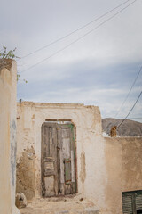 Vertical photo of an abandoned house with a cat near the castle in Pyrgos Kallistis in the island of Santorini, Greece, a picturesque Greek village in mainland perfect for day trip from Fira.