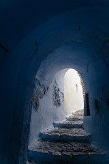 Rustic stone staircase in a whitewashed tunnel, Pyrgos Kallistis, island of Santorini, Greece. Traditional Cycladic architecture with aged walls and light contrast in a charming Greek island alleyway.