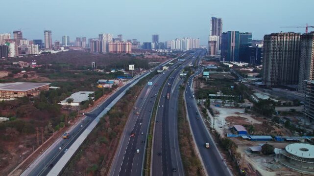 Nehru outer ring road with vehicles and under construction buildings at financial district, nanakramguda, hyderabad, telangana, india. day time, moving up, drone shot, 4k.