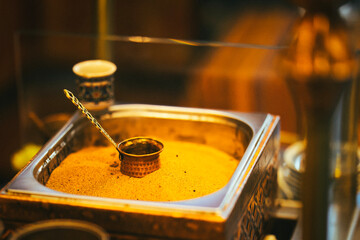 Traditional Turkish coffee brewing in hot sand with a copper cezve, creating an authentic and aromatic experience in a warm, atmospheric setting.