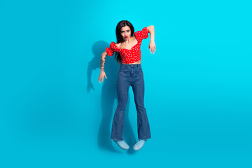 Fashionable young woman posing on a vibrant blue background wearing a stylish outfit, striking a...