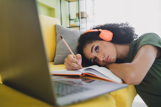 Portrait of nice young girl headphones notepad laptop online class green interior living room flat indoors
