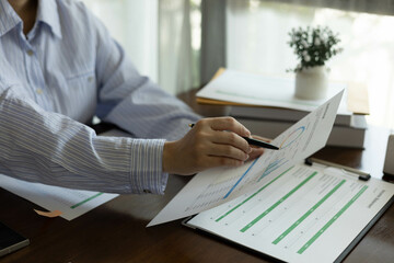 The businessman is sitting at a desk with a calculator and a stack of papers. She is looking at the papers and seems to be deep in thought

