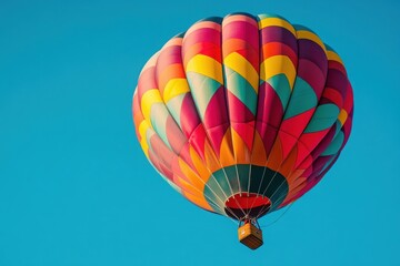 Fototapeta premium Colorful hot air balloon floating peacefully in a vibrant blue sky on a beautiful sunny day above