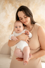 a mother holds a newborn baby in her arms, a mother gently hugs and kisses a small child, maternal love and care, a mom and a baby