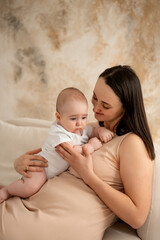 a mother holds a newborn baby in her arms, a mother gently hugs and kisses a small child, maternal love and care, a mom and a baby