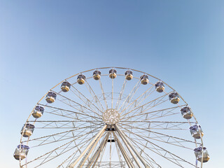 white ferris wheel on clear blue sky. white color. calm tones. blue and white. white illumination. minimalistic blue sky background