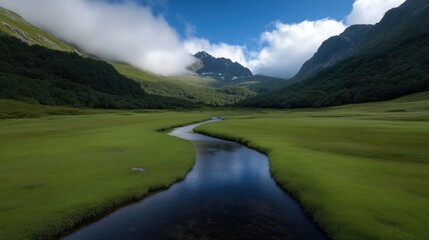 Serene mountain valley with meandering stream. Lush green meadows and misty mountains