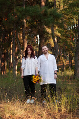 Obraz premium Happy couple standing in a forest on a sunset