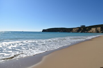 Sunny Beach Paradise Turquoise Water Meets Sandy Shores Under Clear Blue Sky, Peaceful Horizon With Sailboat Cliffside Building