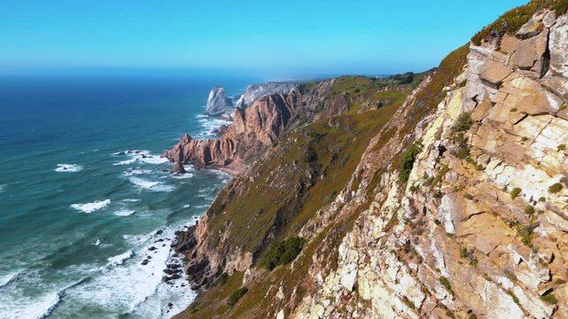 View of the horizon of the stormy Atlantic Ocean with rocky shores and a lighthouse from the Cape Roca in Portugal. 4K video