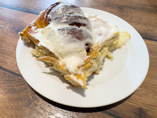 Homemade cinnamon rolls with creamy icing on white plate